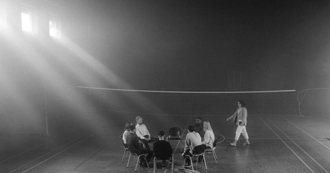 grayscale photo of people sitting on the chairs